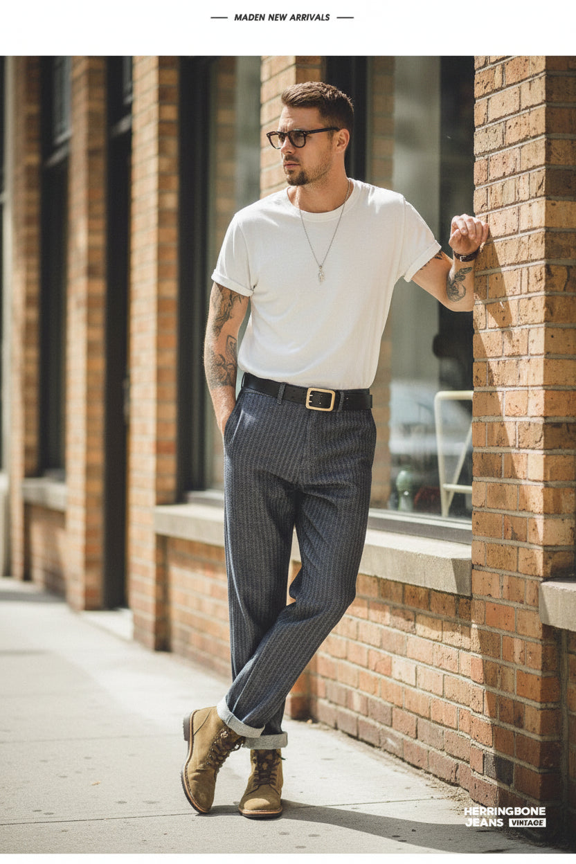 Person wearing a beige shirt, dark striped pants, and brown boots standing in front of a wooden door.