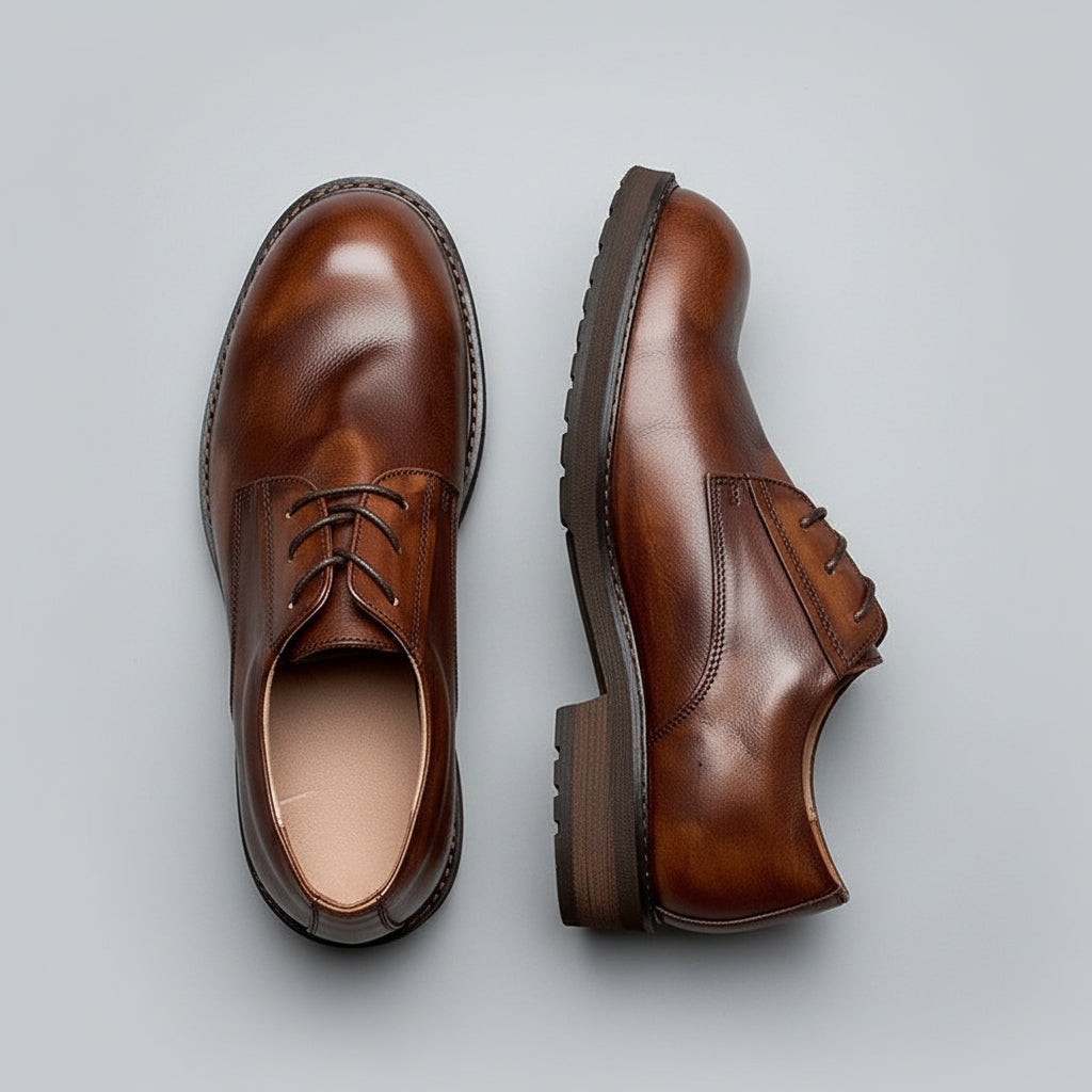 Pair of brown leather shoes on a wooden surface with a knife and other items.