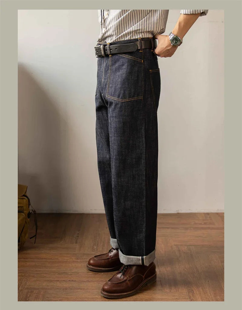 Person wearing dark blue jeans and brown shoes in a minimal indoor setting