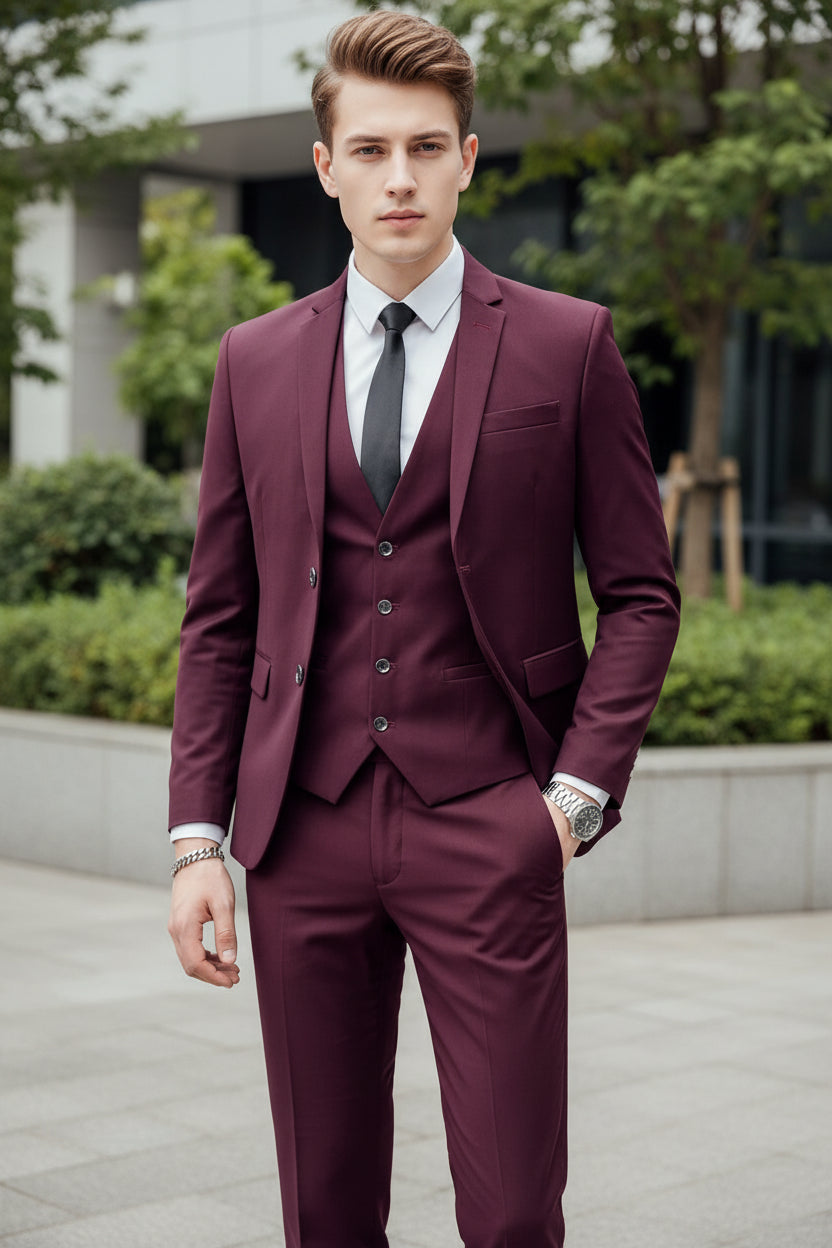 Man wearing a burgundy suit with a white shirt and black tie against a metallic background