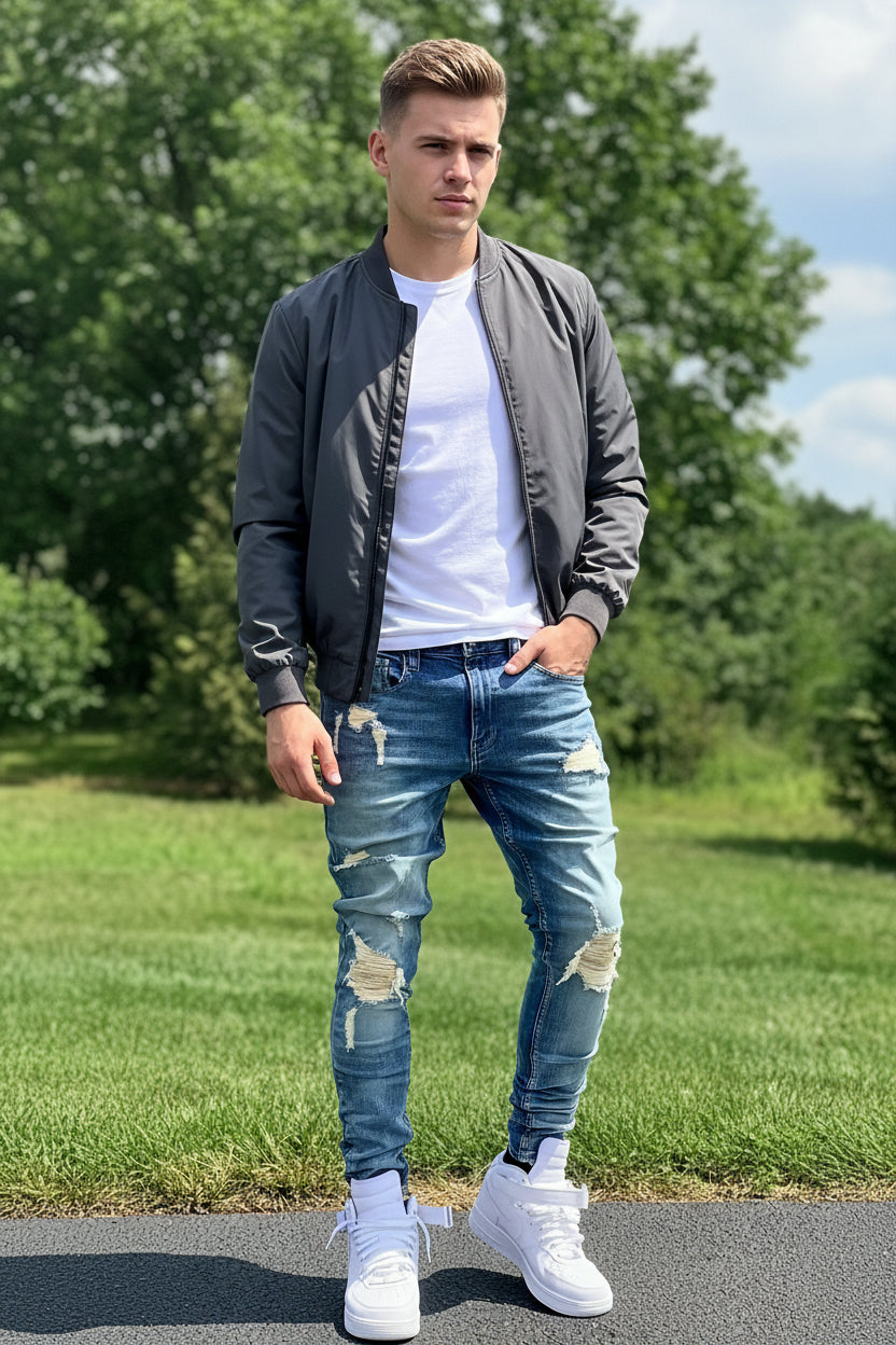 Person wearing distressed blue jeans and white sneakers on a grassy background