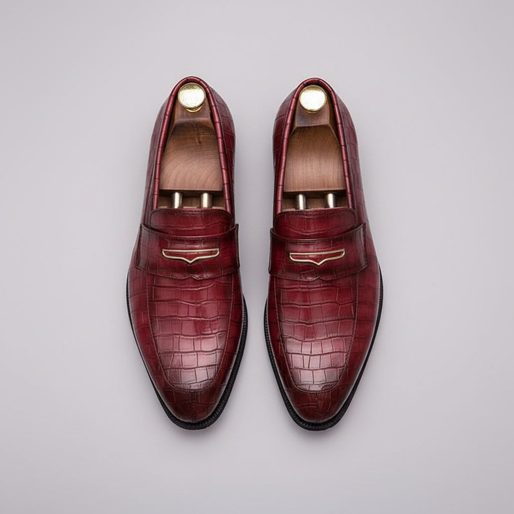 Pair of maroon loafers with gold accents on a grid background