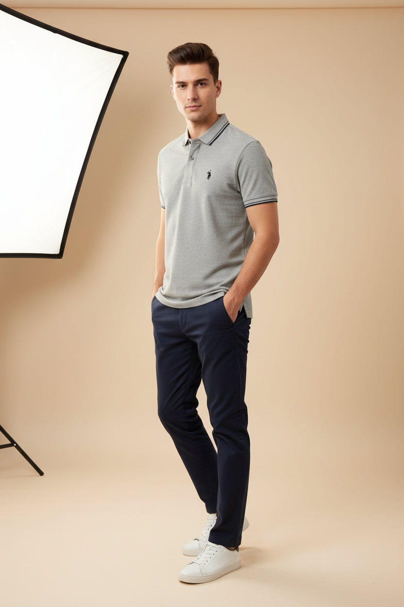 Gray polo shirt with a brand logo held by a hand in a clothing store.