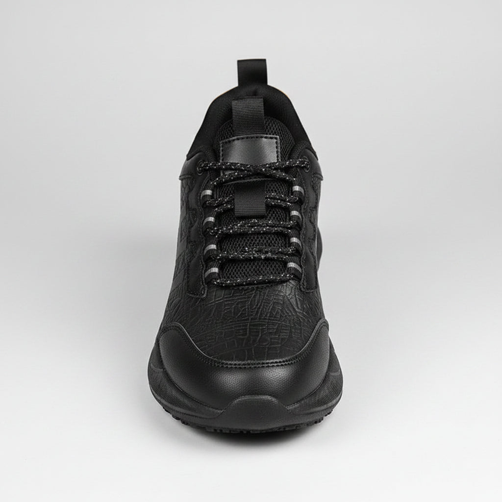 Person tying a black sneaker on a wooden floor with a blurred background