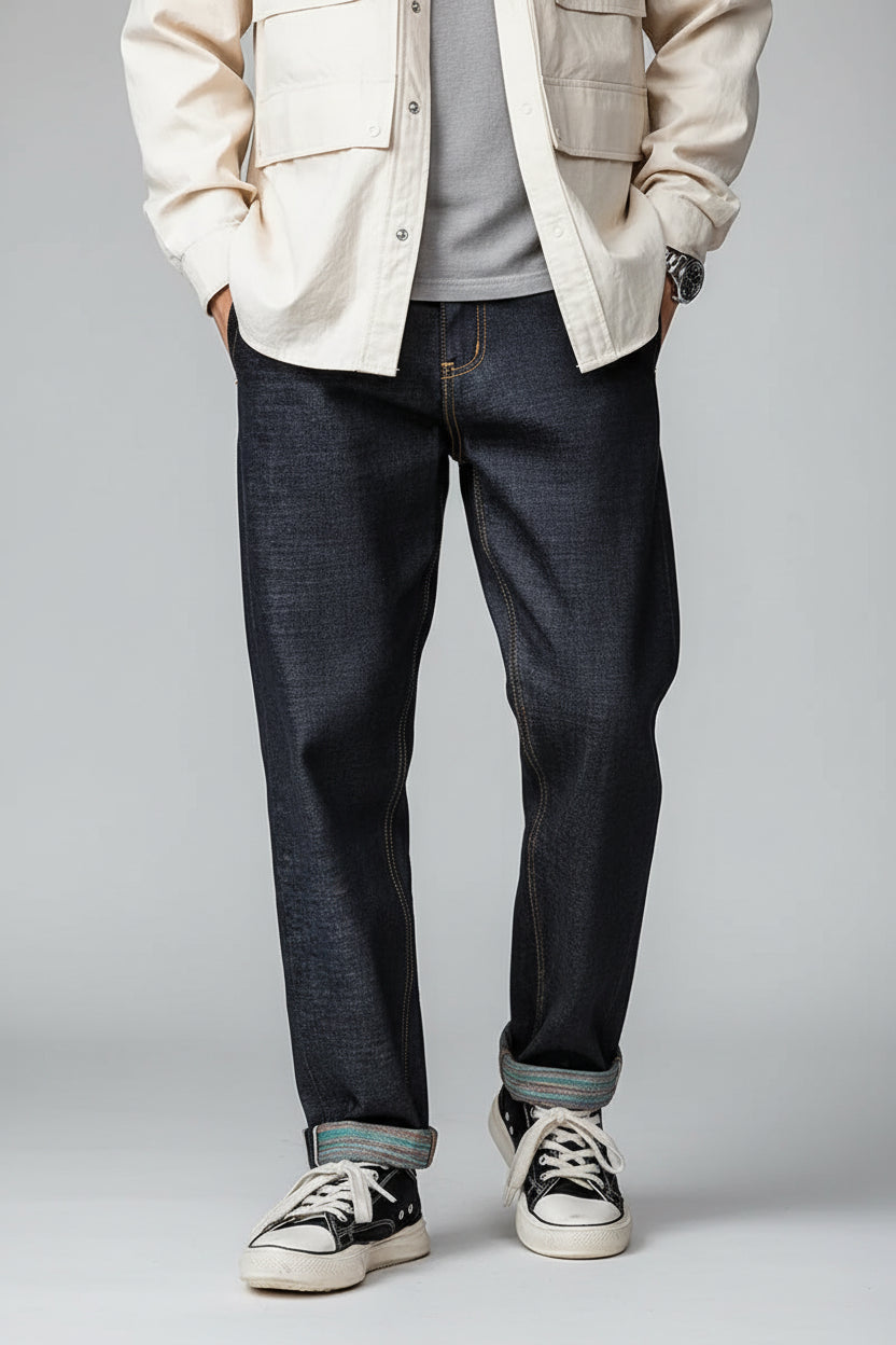 Person wearing raw denim jeans with a brand logo on a brown background