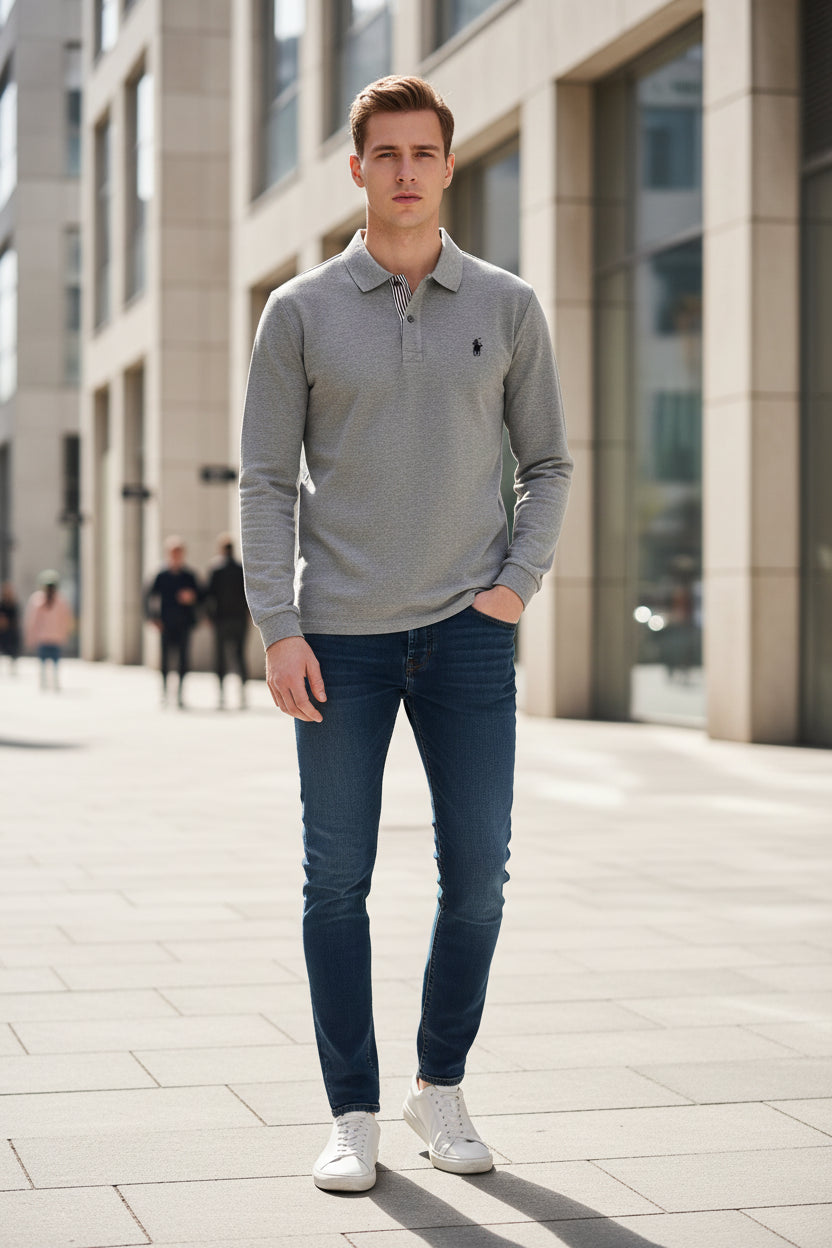 Gray polo shirt with a brand logo held by a hand, on a hanger against a blurred background.