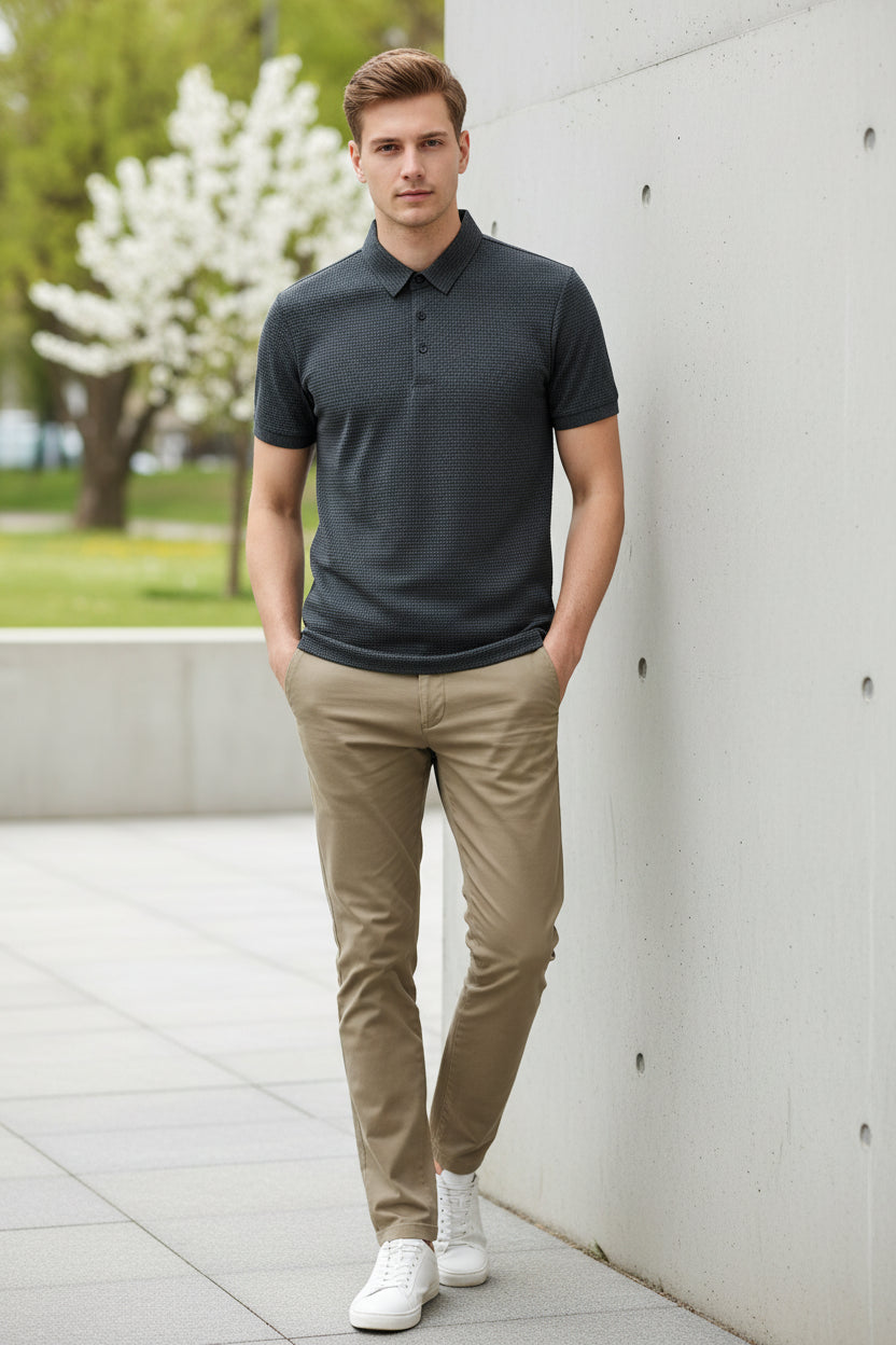 Gray textured polo shirt on a hanger with a hand touching the fabric.