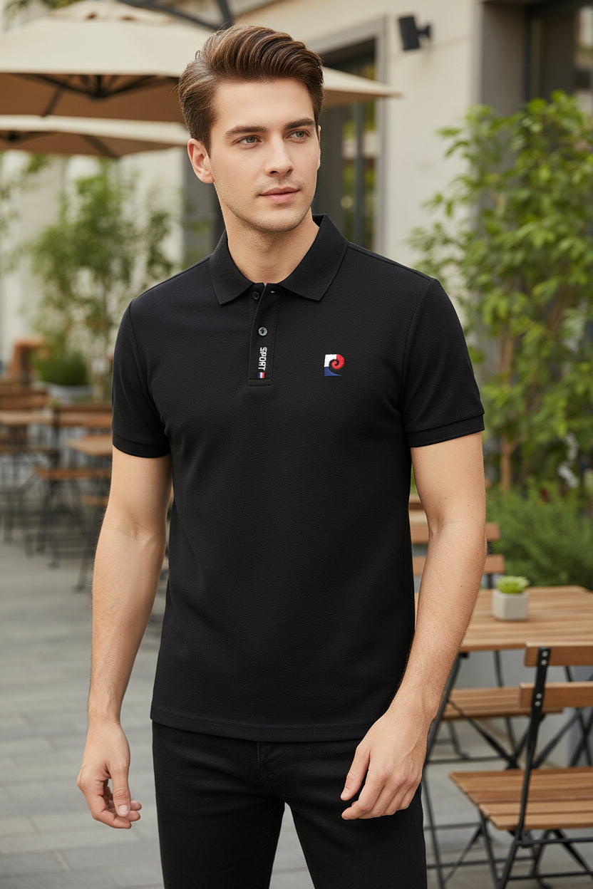 Black polo shirt with brand logo held by a hand against a blurred clothing store background
