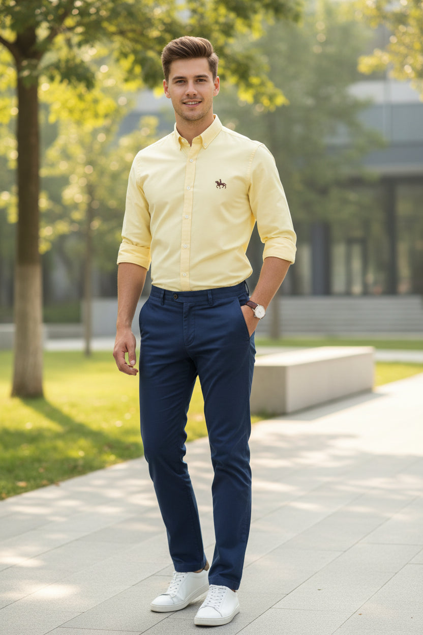 Folded light yellow shirt with a small logo on a gray textured background