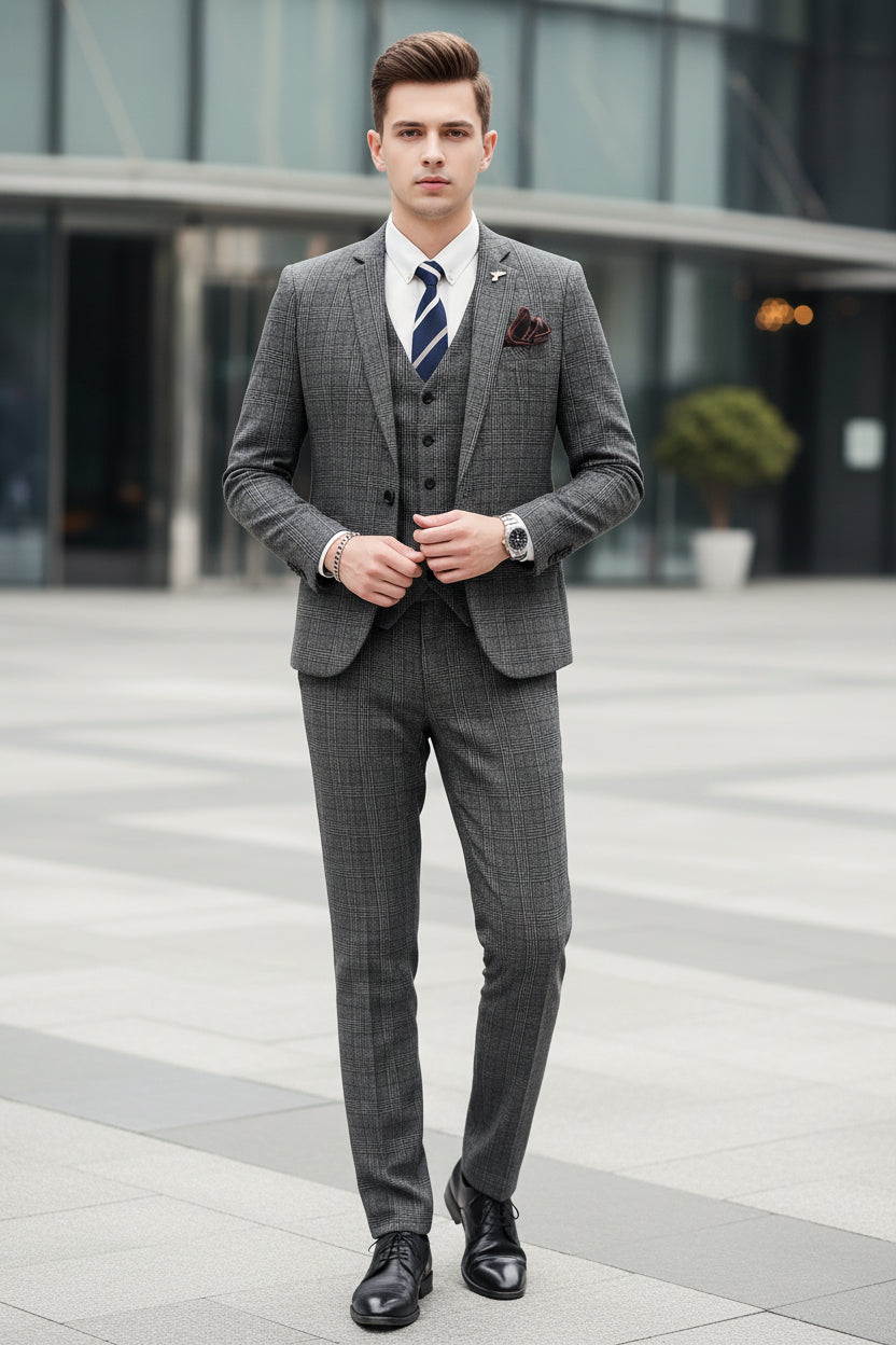 Man wearing a gray checkered suit with a white shirt and striped tie, holding a phone, standing against a marble wall.
