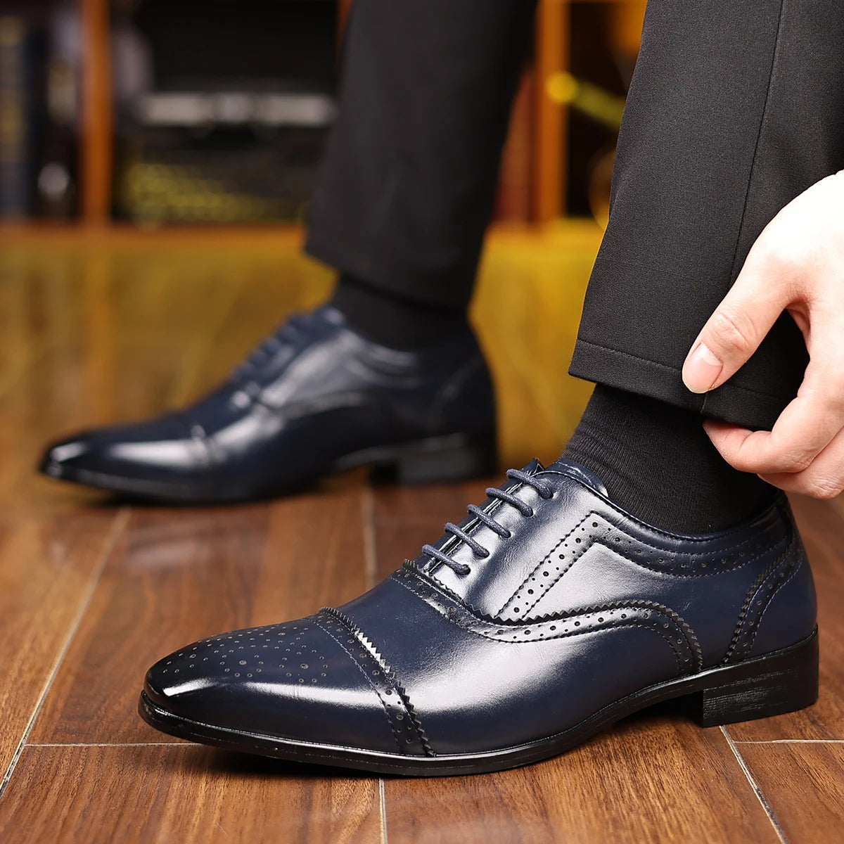 Person wearing navy blue dress shoes on a wooden floor