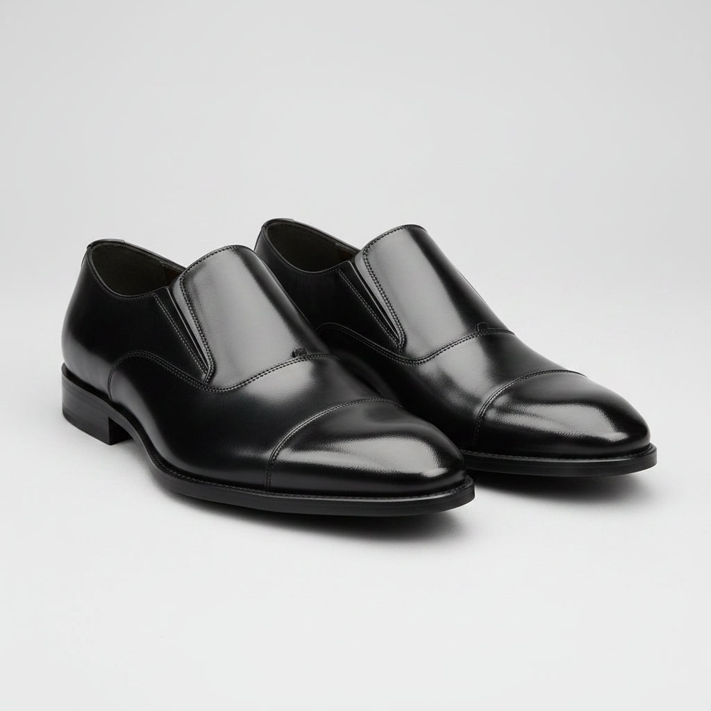 Black dress shoes worn with black pants on a gray background