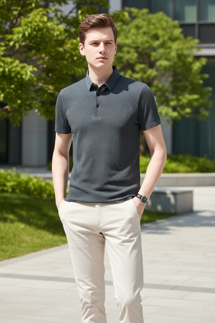 Man wearing a patterned dark green polo shirt against a gray background