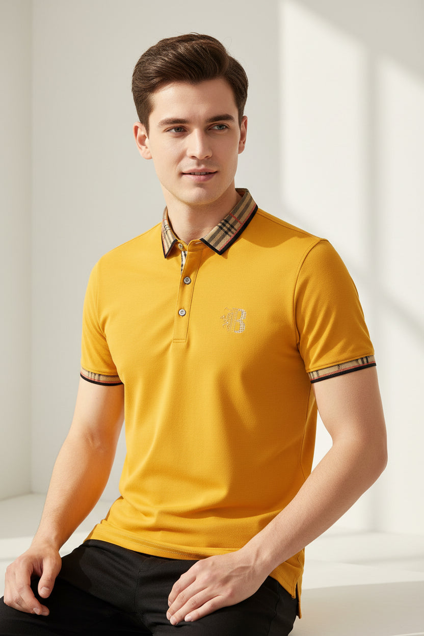 Yellow polo shirt with plaid collar and watch on a gray surface