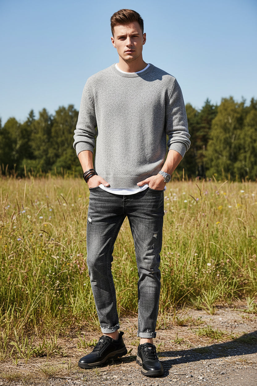 Black leather shoes worn with rolled-up jeans on a gray background