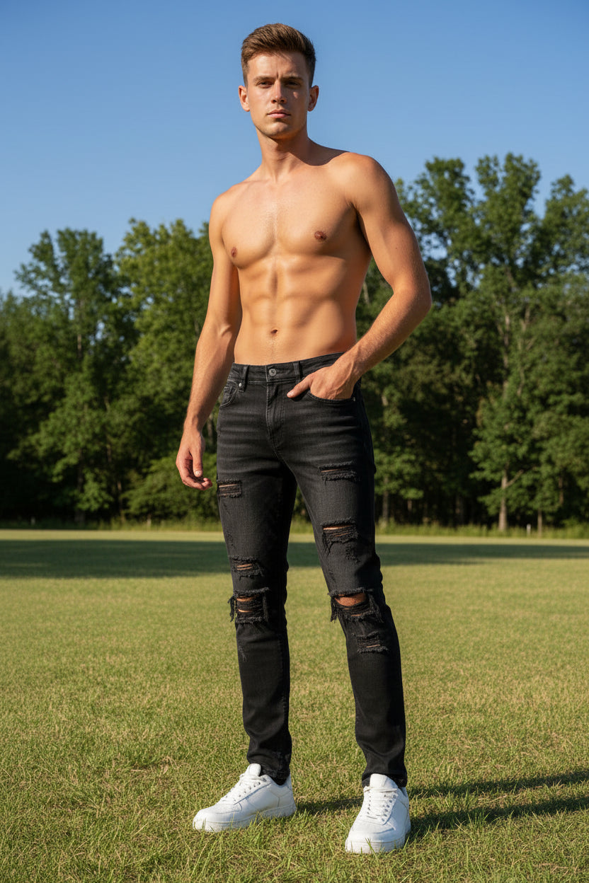Person wearing black distressed jeans and white sneakers on a grassy background