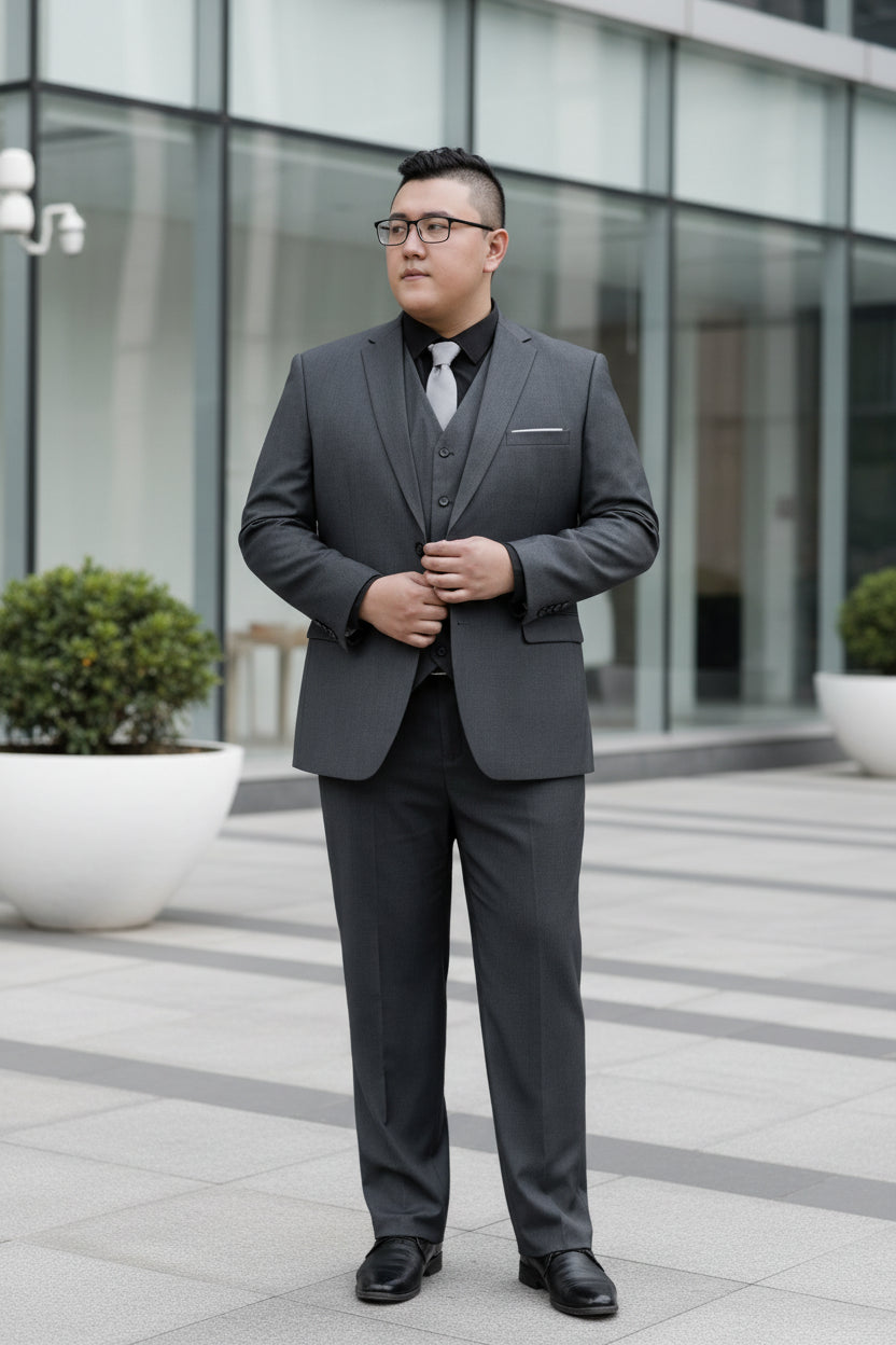 Man wearing a gray suit with a vest and tie, standing in front of a glass door.