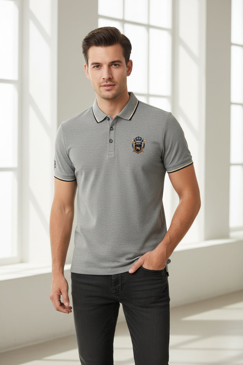 Gray polo shirt with a logo and a watch on a gray surface