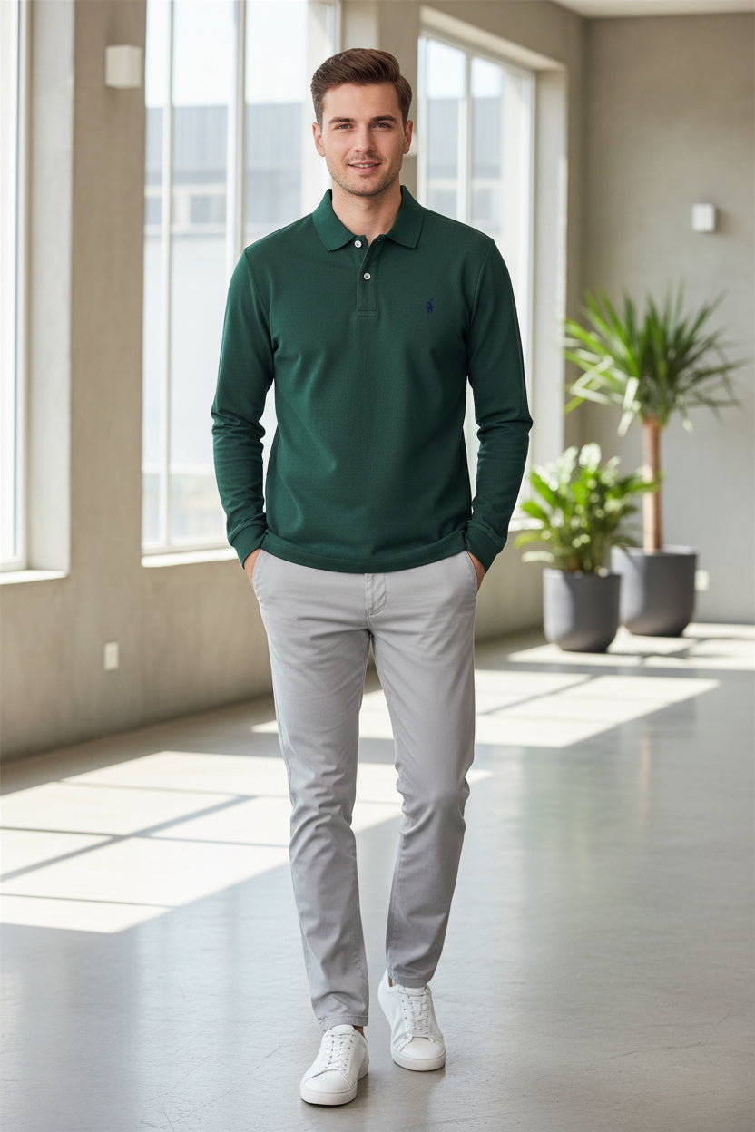 Green polo shirt with a brand logo held by a hand, with other shirts in the background.