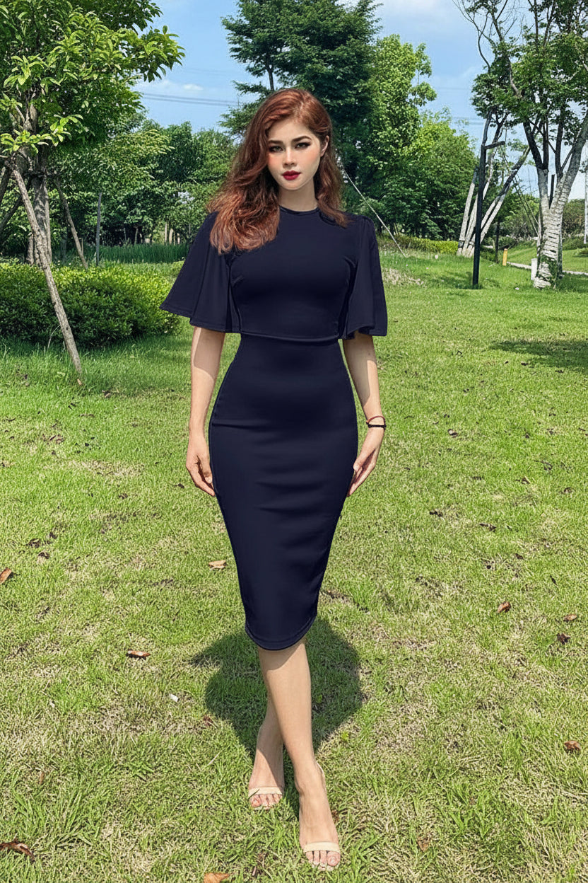Woman in a navy blue dress standing in a grassy area with trees in the background