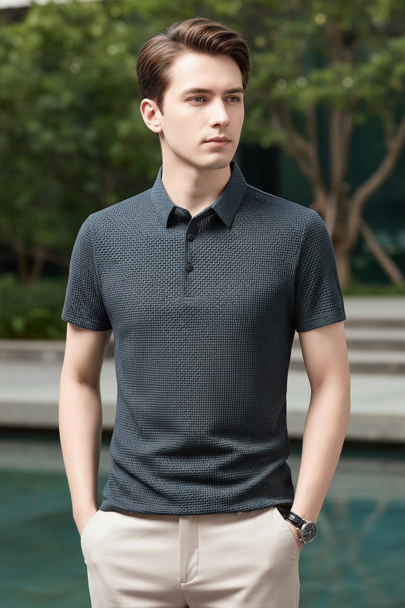 Man wearing a dark patterned polo shirt against a gray background