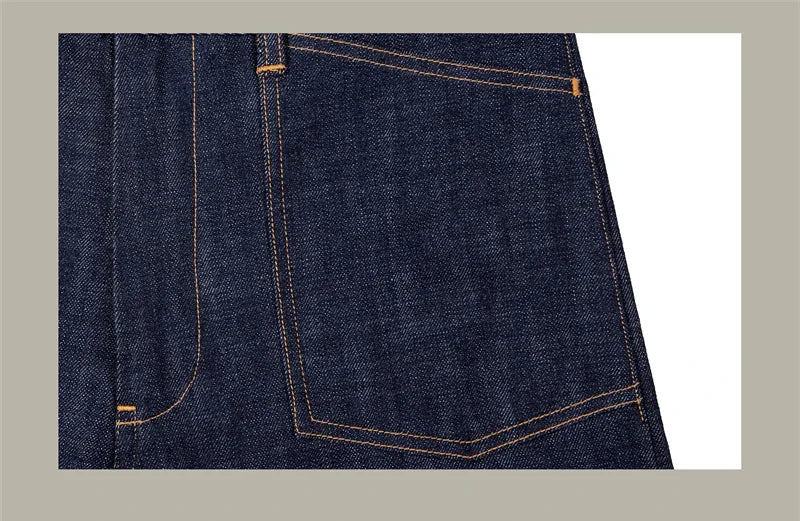 Close-up of dark blue denim fabric with visible stitching on a light gray background