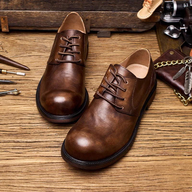 Brown leather shoes on a wooden surface with vintage tools and accessories.
