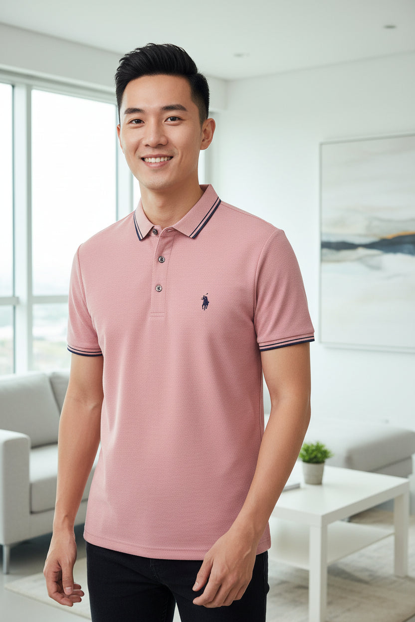 Pink polo shirt with a brand logo hanging on a rack with other shirts.
