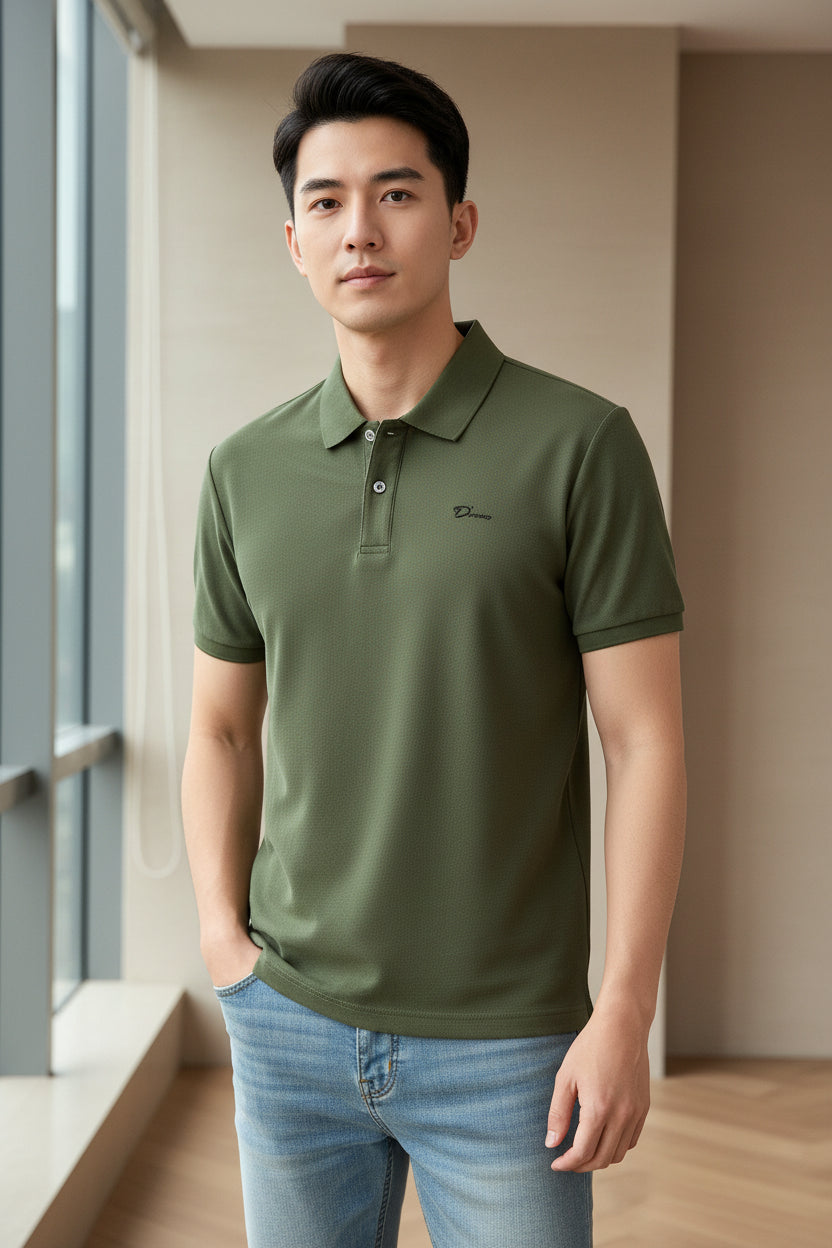Green polo shirt with a brand logo held by a hand on a rack of other shirts.