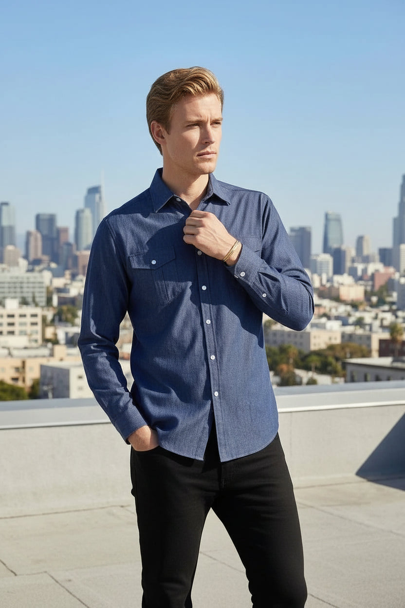 Man wearing a blue shirt on a rooftop with a city skyline in the background