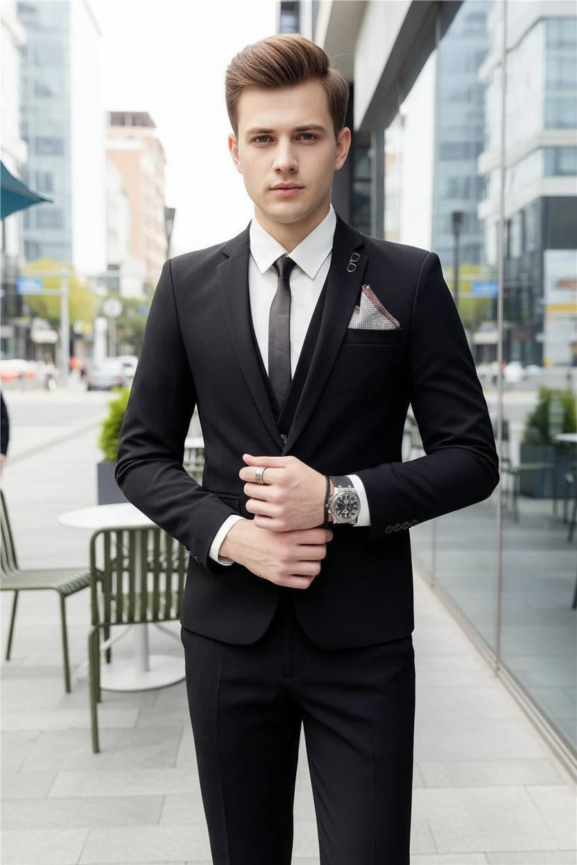 Man wearing a black suit with a white shirt and tie, standing in front of a glass door.