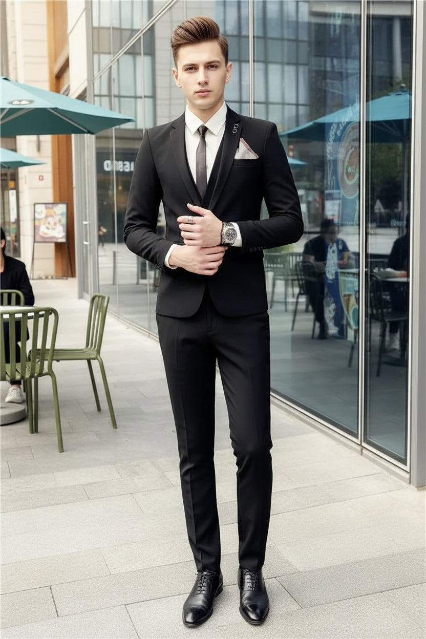 Man wearing a black suit with a white shirt and tie, standing in front of a glass door.