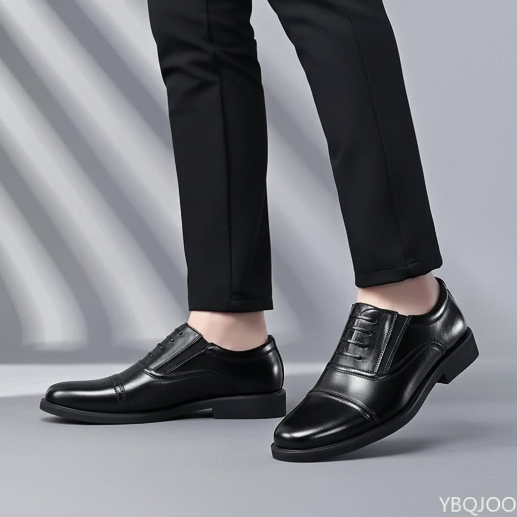 Black leather dress shoes worn with black pants on a gray background
