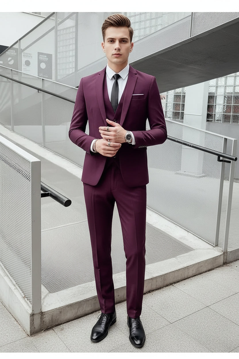 Man wearing a purple suit with a white shirt and black tie in an indoor setting.
