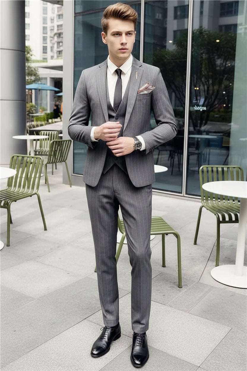 Person wearing a gray suit with a white shirt and black tie in an outdoor setting.