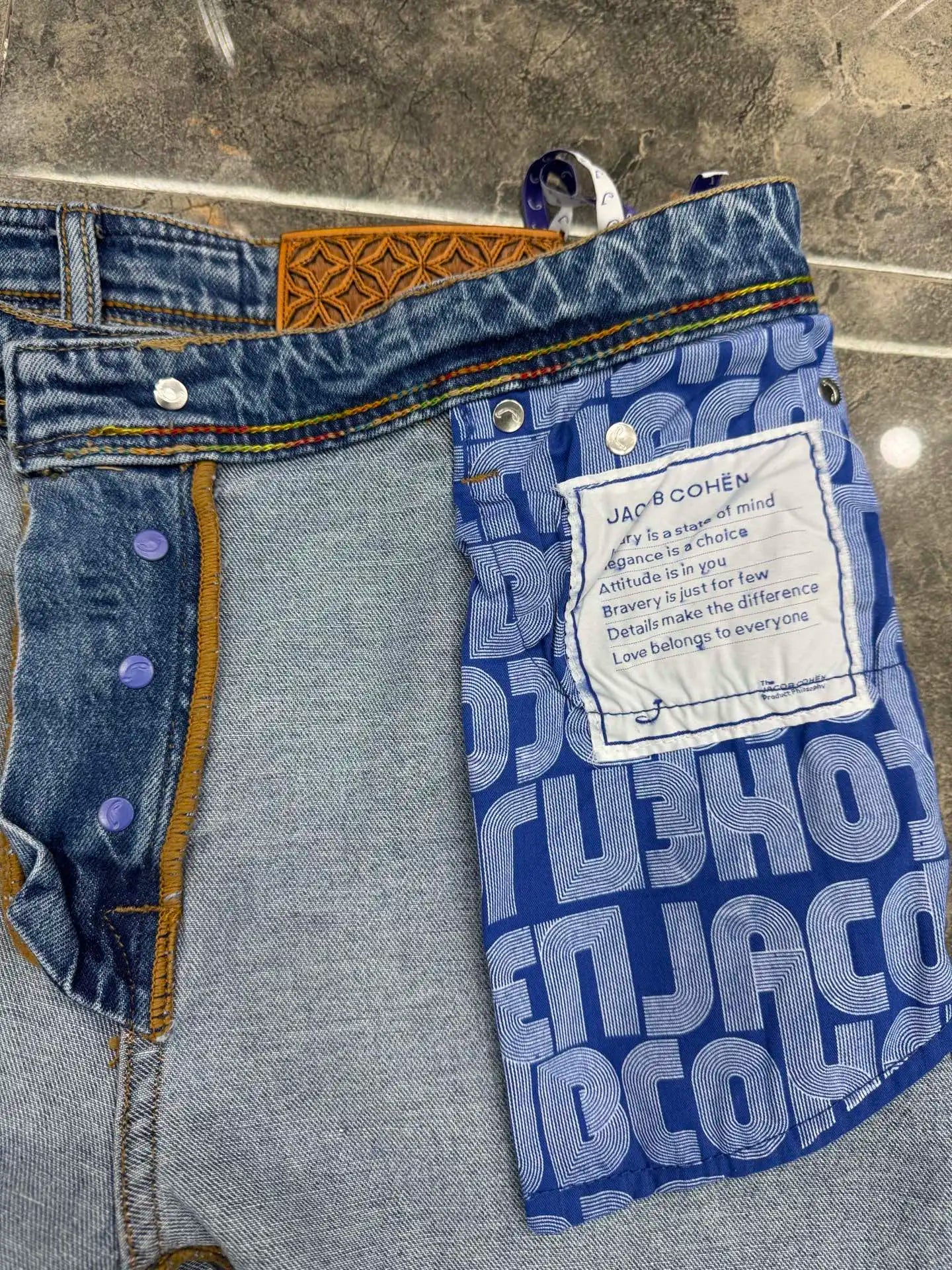 Close-up of a blue denim garment with a brand label on a gray surface