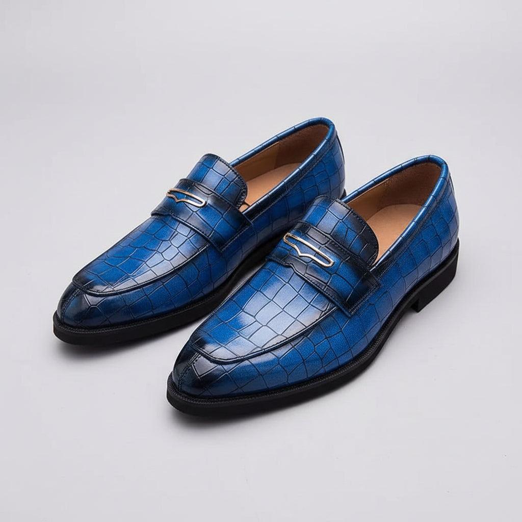Blue crocodile-patterned loafers on a grid background