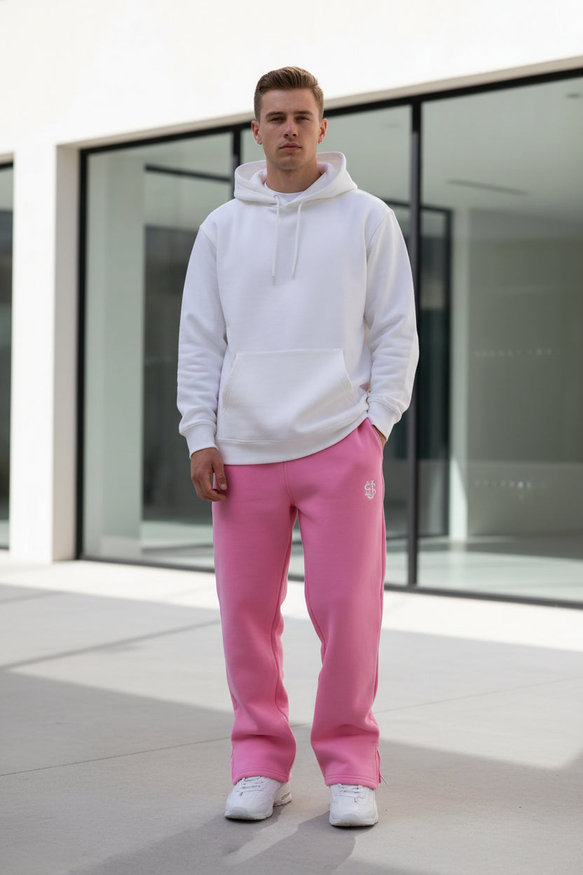 Person wearing pink sweatpants with a logo in a minimal indoor setting