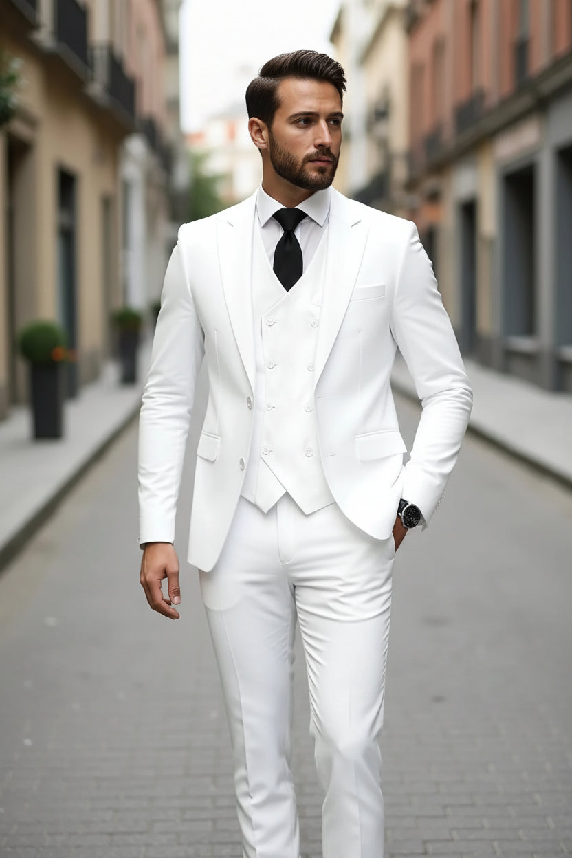 Man wearing a white suit with a black tie on a city street.