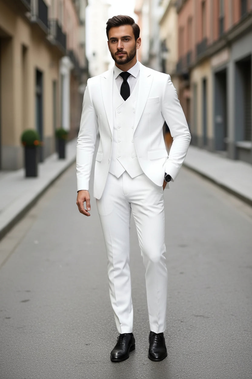 Man wearing a white suit with a black tie on a city street.