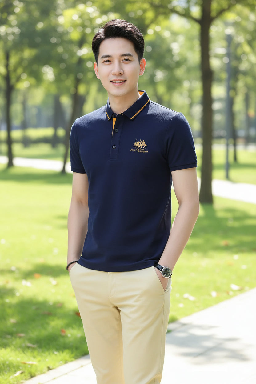 Man wearing a navy blue polo shirt with yellow accents on a gray background