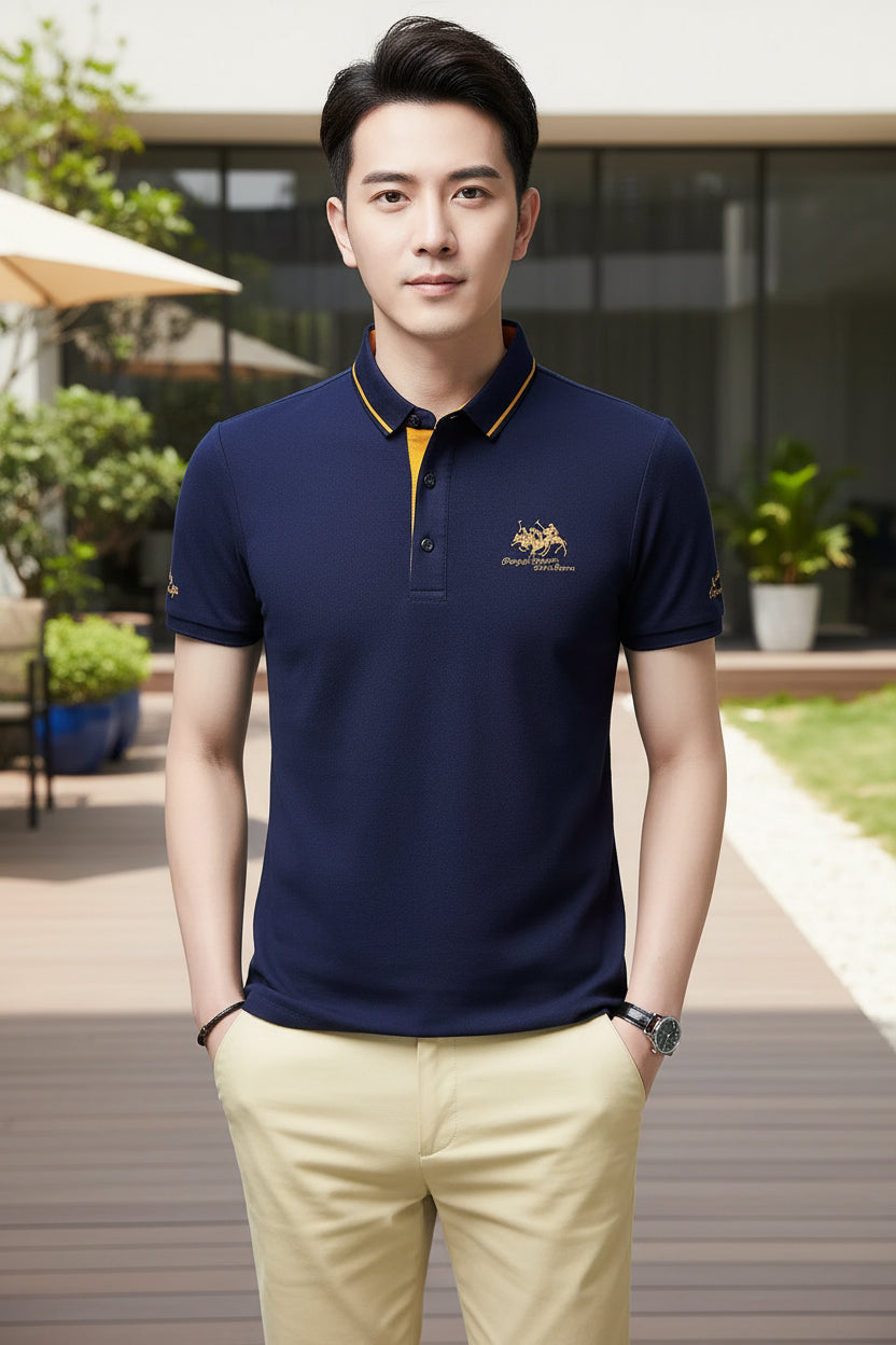 Man wearing a navy blue polo shirt with yellow accents on a gray background