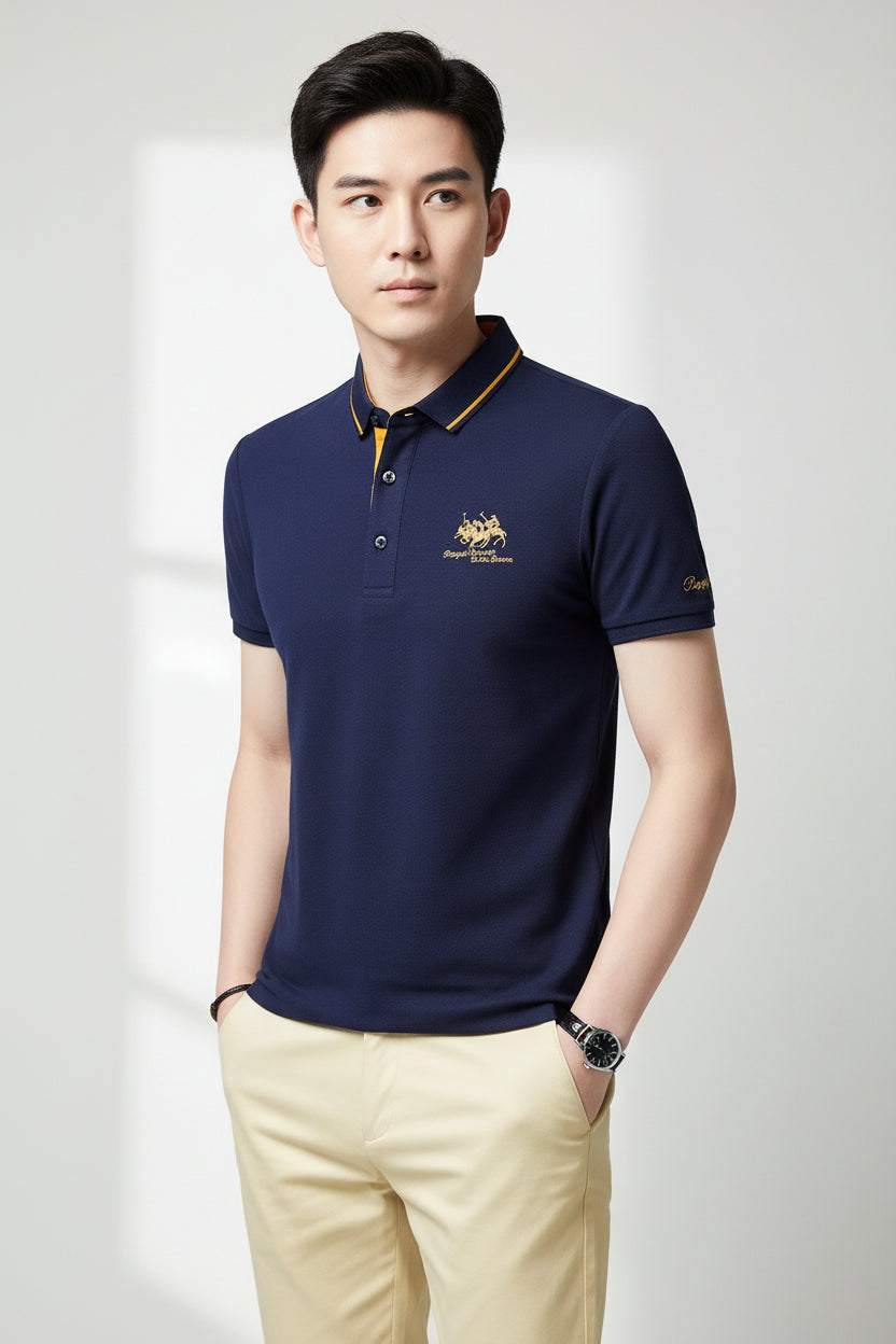 Man wearing a navy blue polo shirt with yellow accents on a gray background