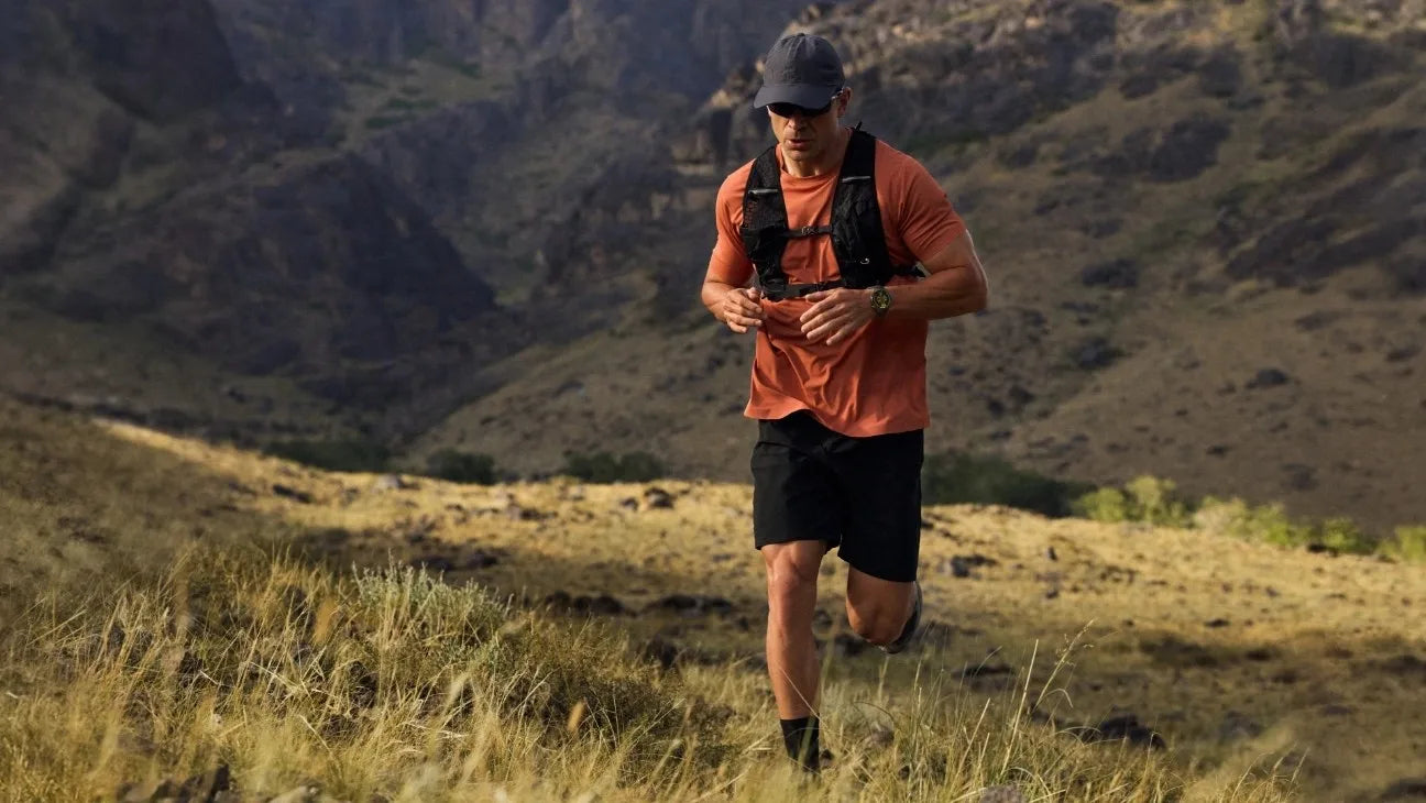 Man running on a mountain trail with a scenic background
