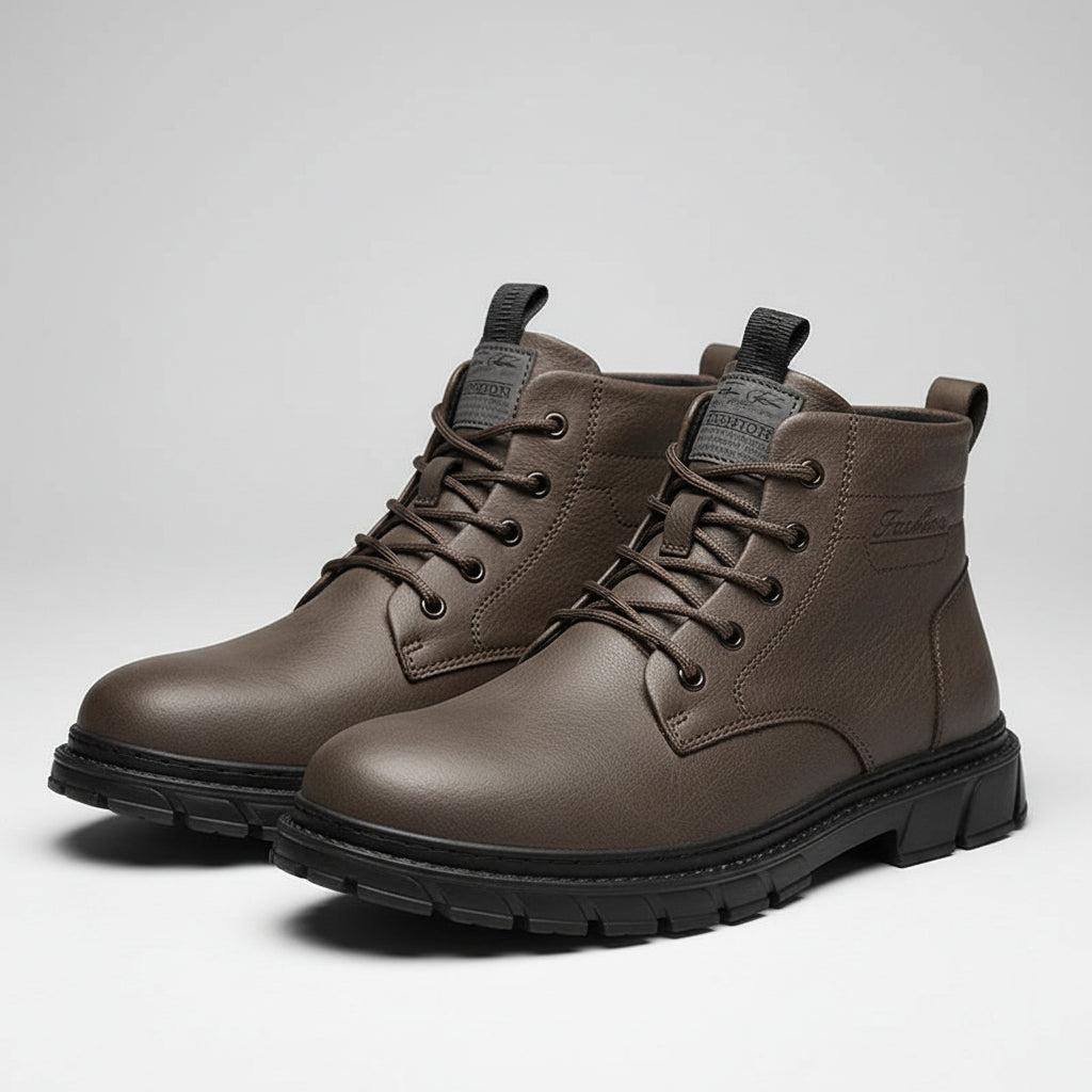 Brown leather boots with black soles on a brown surface