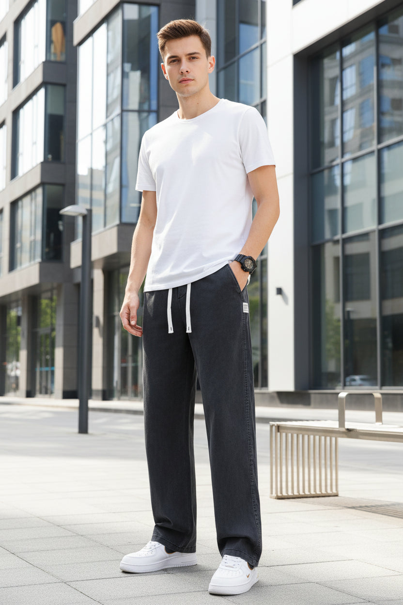 Person wearing black wide-leg pants with white sneakers on a gray background