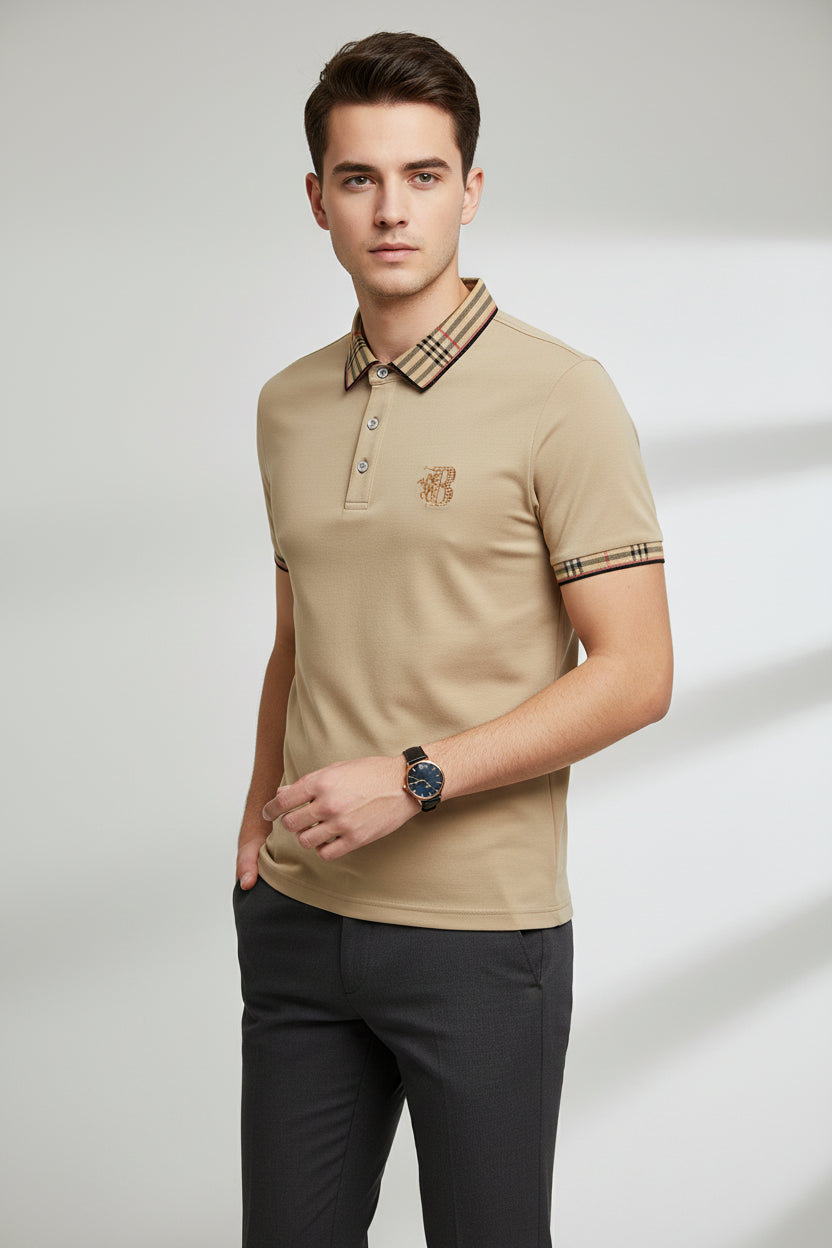 Beige polo shirt with plaid collar and brand logo, accompanied by a watch on a gray surface.
