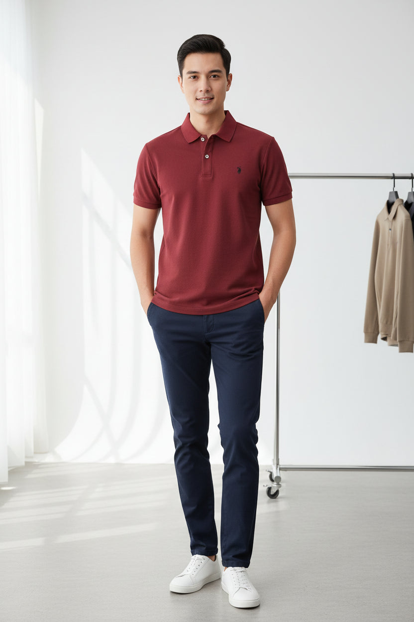 Red polo shirt with Ralph Lauren logo held by a hand, with other shirts in the background.