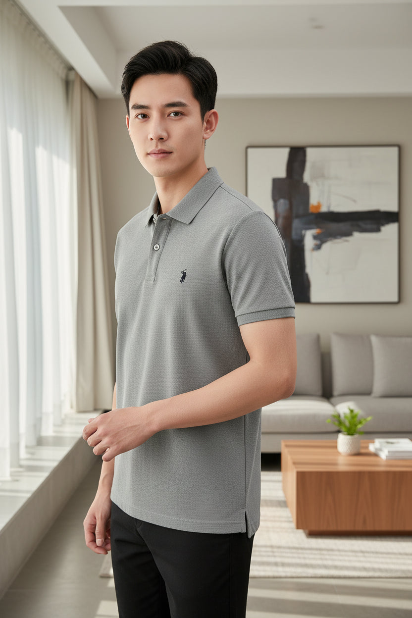 Gray polo shirt with a brand logo held by a hand, hanging against a neutral background.