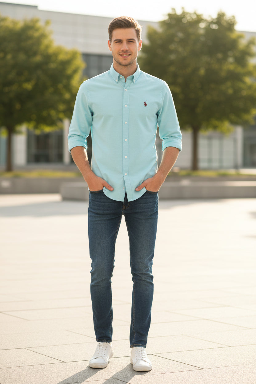 Folded light blue shirt with a small logo on a gray surface
